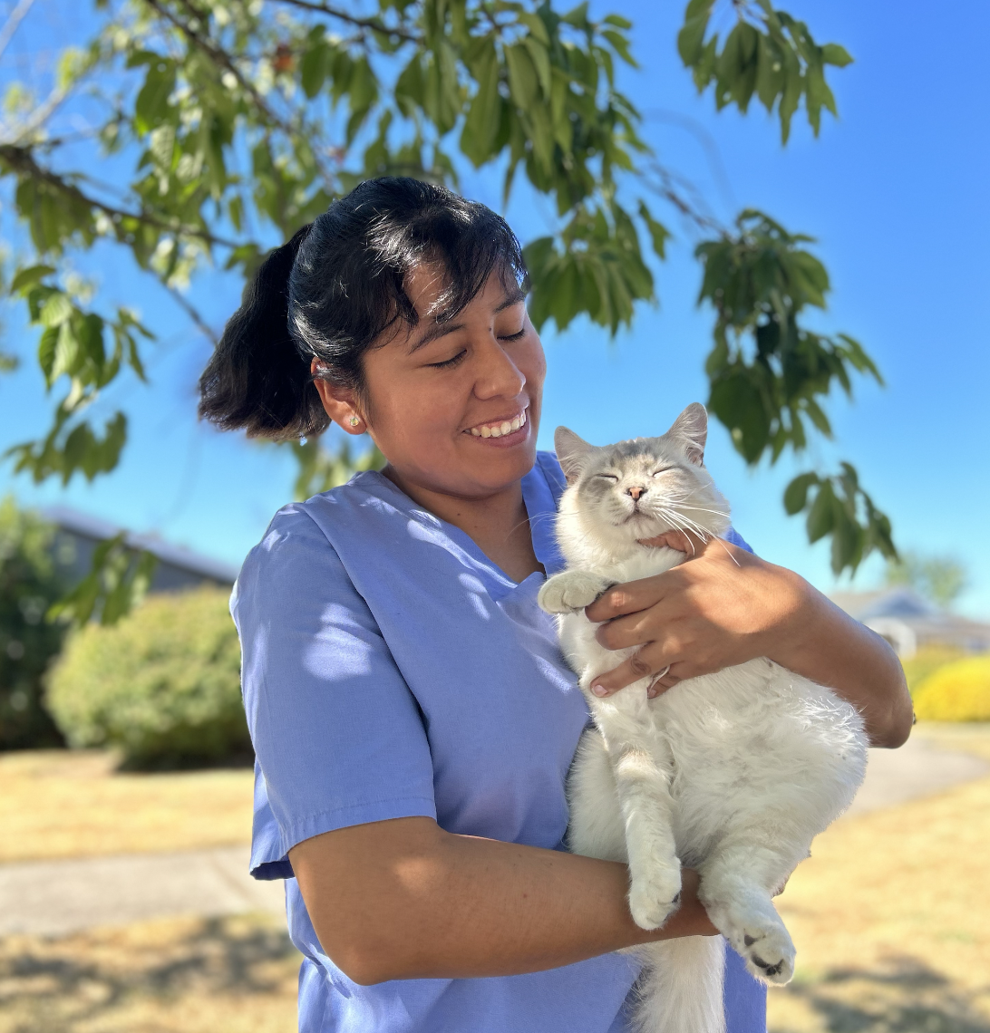 A happy vet assistant holding a cat outside